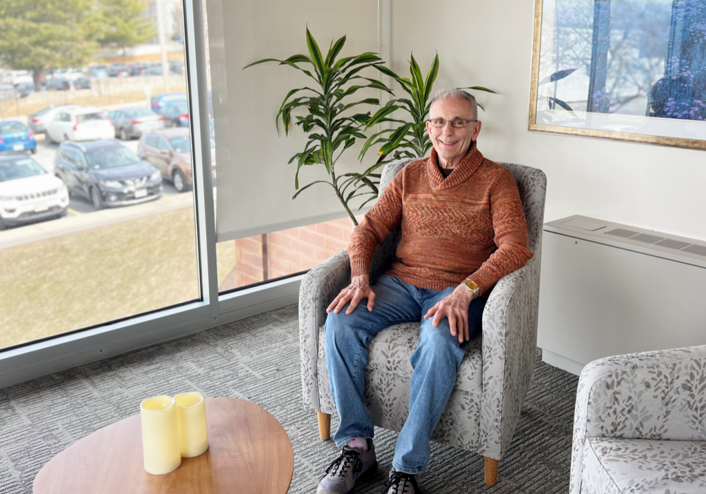 Male hospice volunteer shares his journey from caregiver to volunteering. He's sitting in a tranquil room