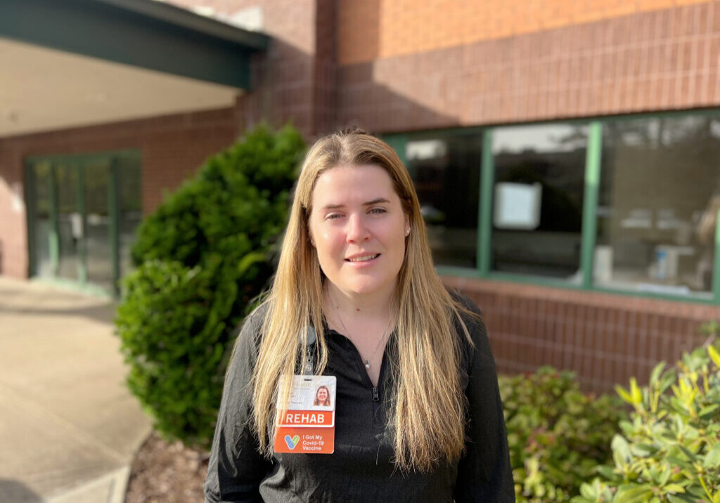 Photo of a physical therapist standing in front of a brick building