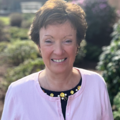 Woman in pink sweater smiling in a garden