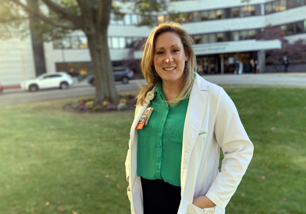 woman in white lab coat standing outside hospital