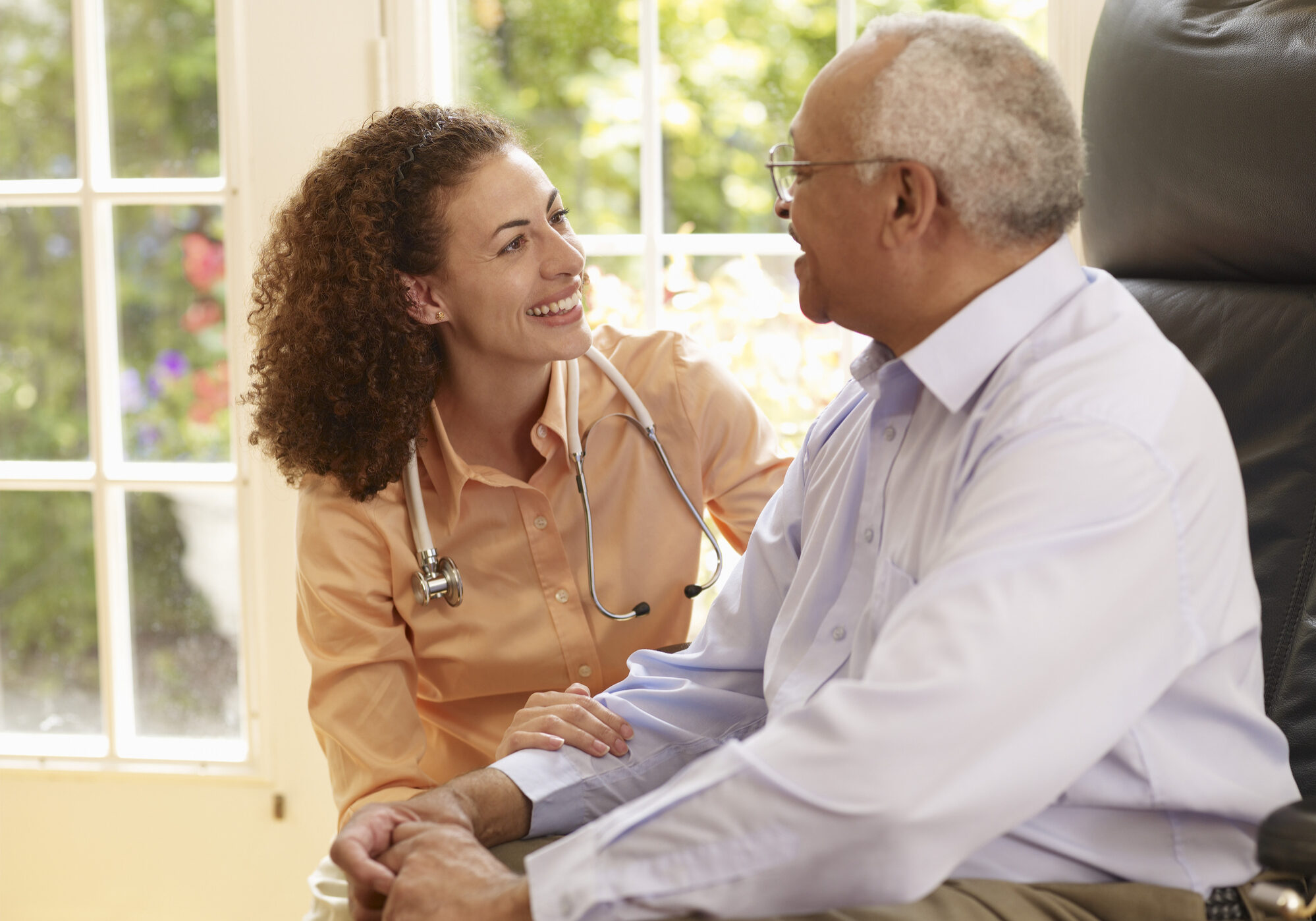 Picture of an elderly black patient meeting with a young black doctor wearing a stethoscope