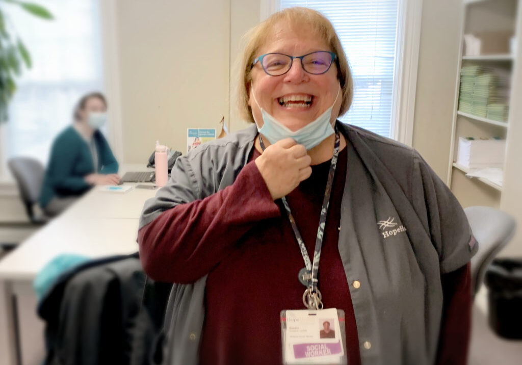 Hospice social worker pulls down her surgical mask to show a warm smile