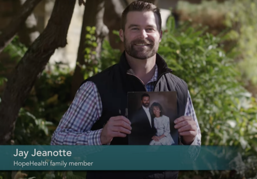 Photo of a man holding up a photo of his parents