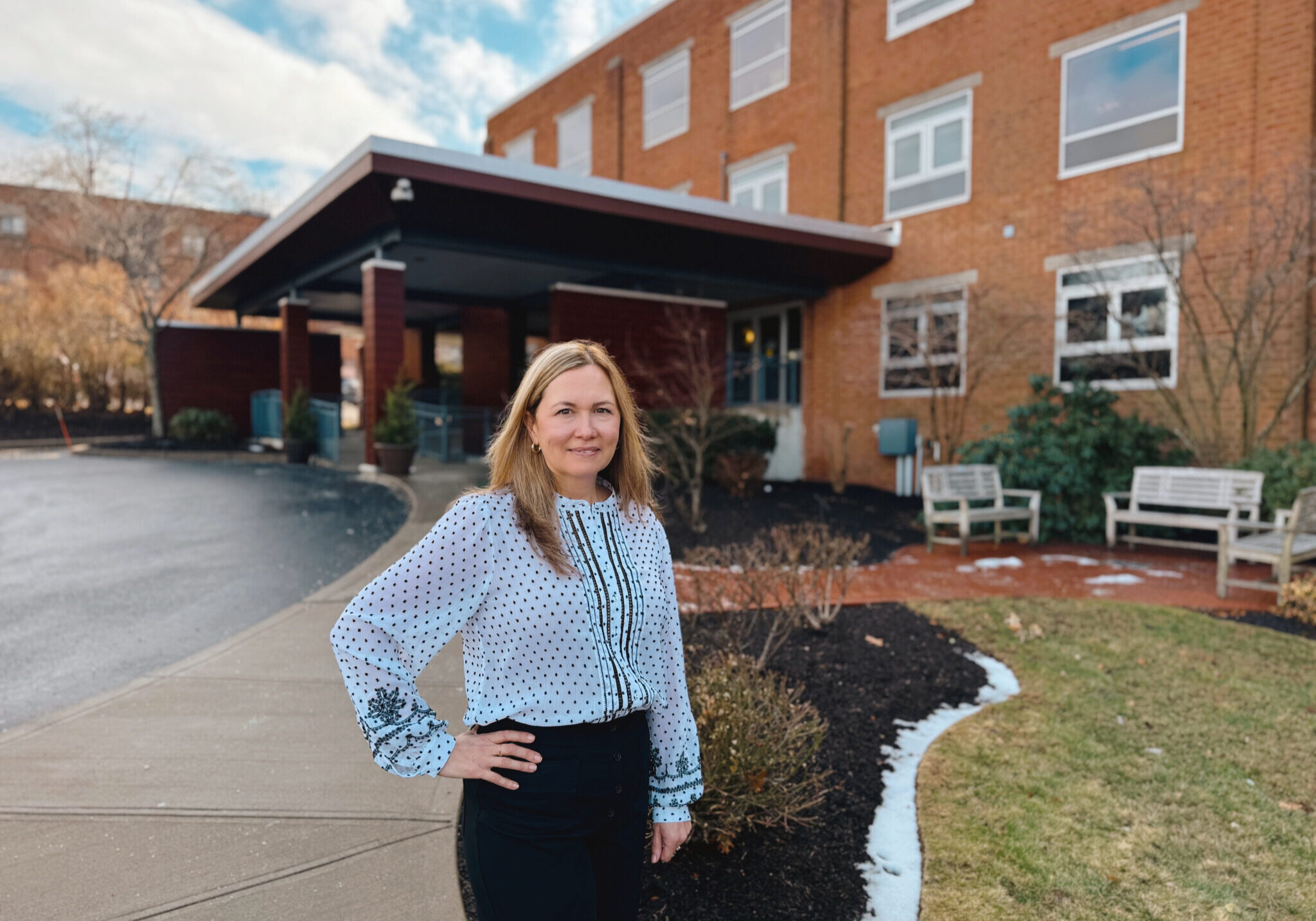 Female pharmicist standing in front of brick Hulitar Hospice Center in Providence, RI