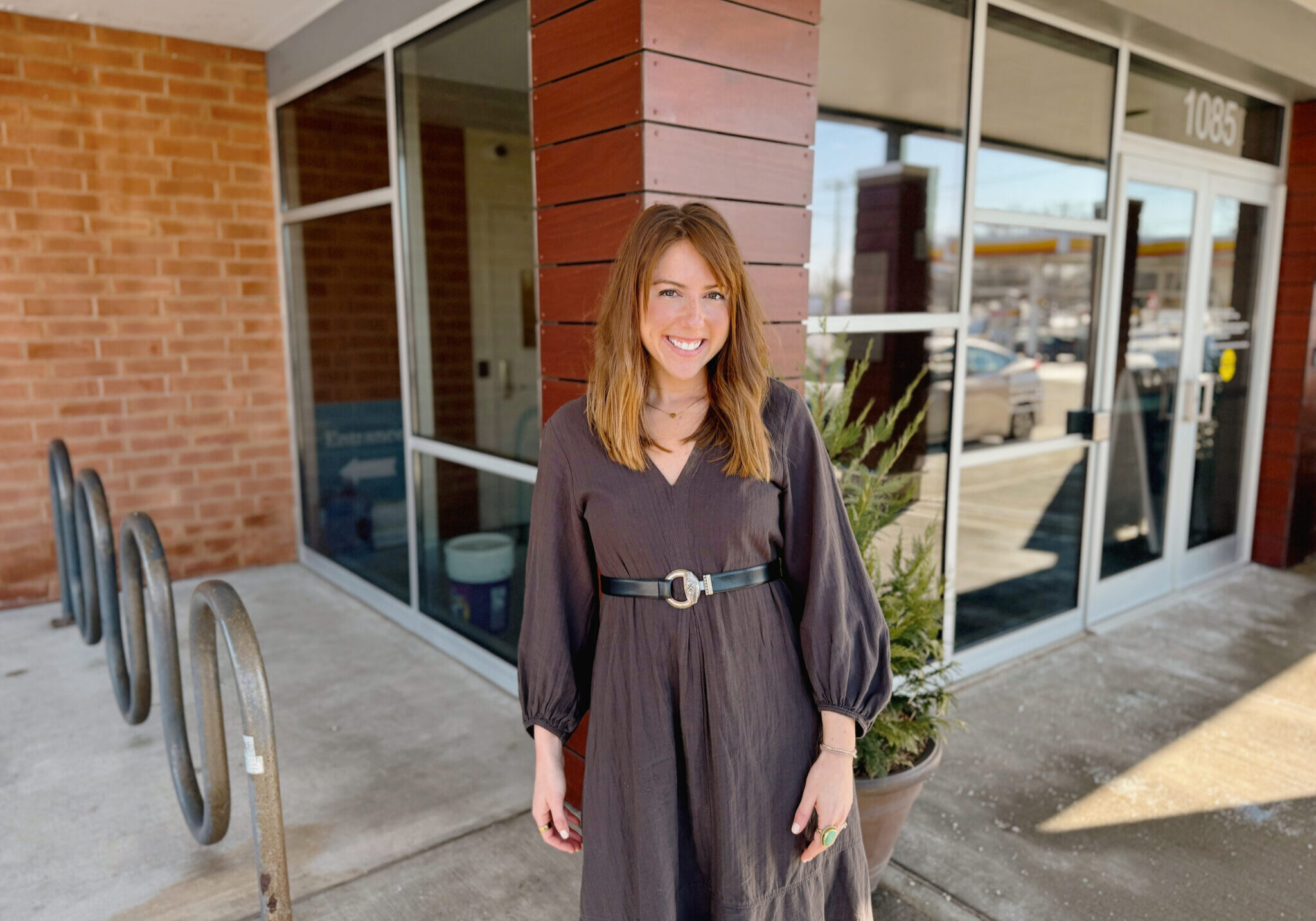 woman standing outside a brick building with large windows
