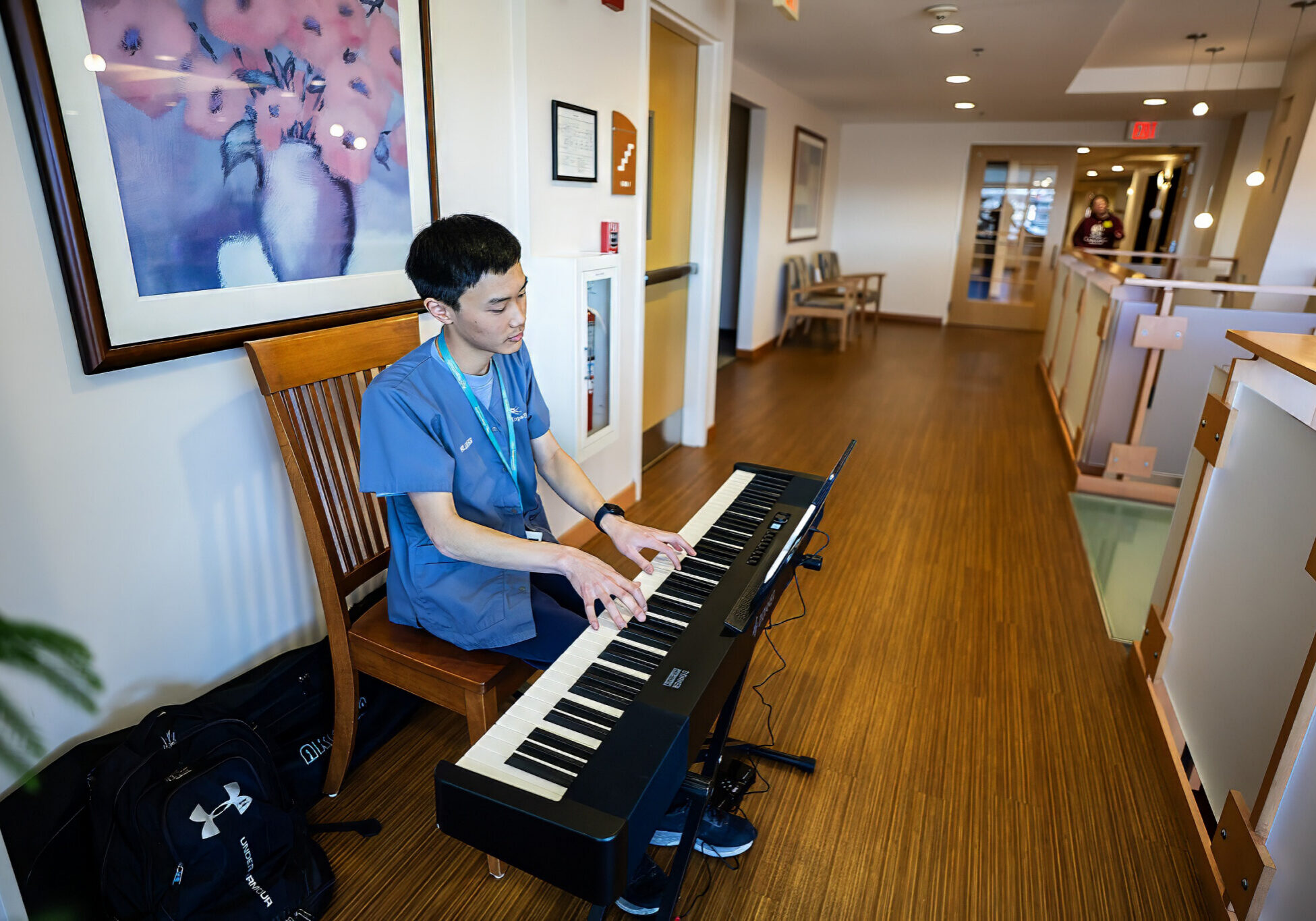 young musician volunteer sits at keyboard at the Hulitar Hospice Center playing music for patients and families