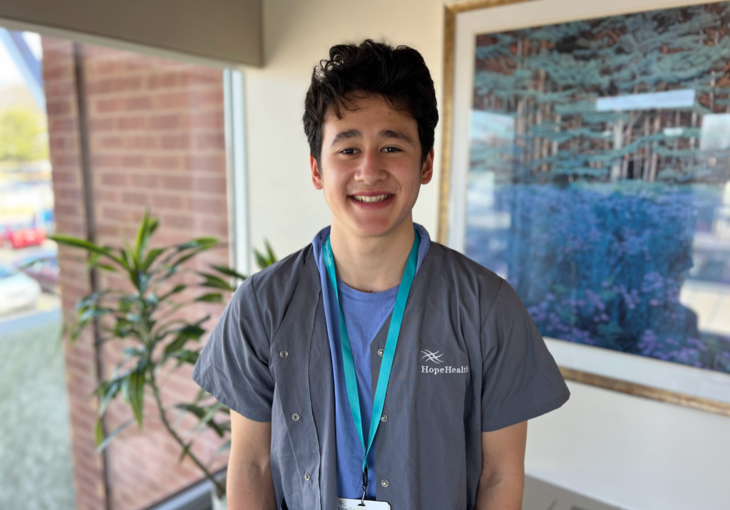 Young volunteer smiling in room with plant and painting behind him