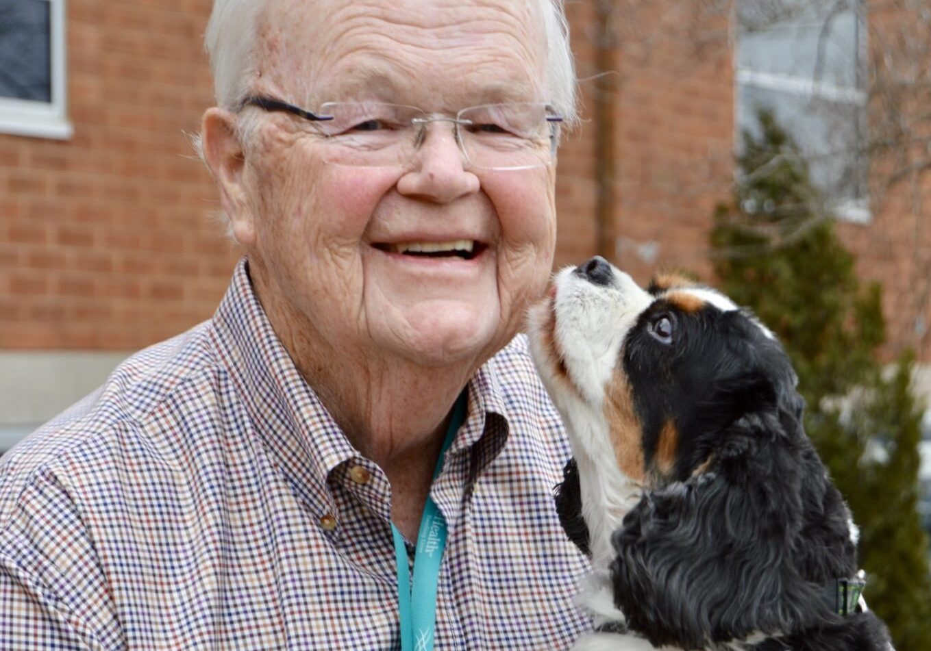 King Charles Spaniel licks the face of an elderly man