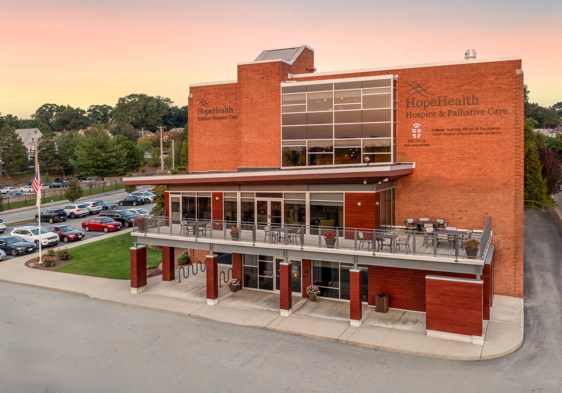 Exterior shot of the Hulitar Hospice Center, a beautiful brick building with the sun setting behind it