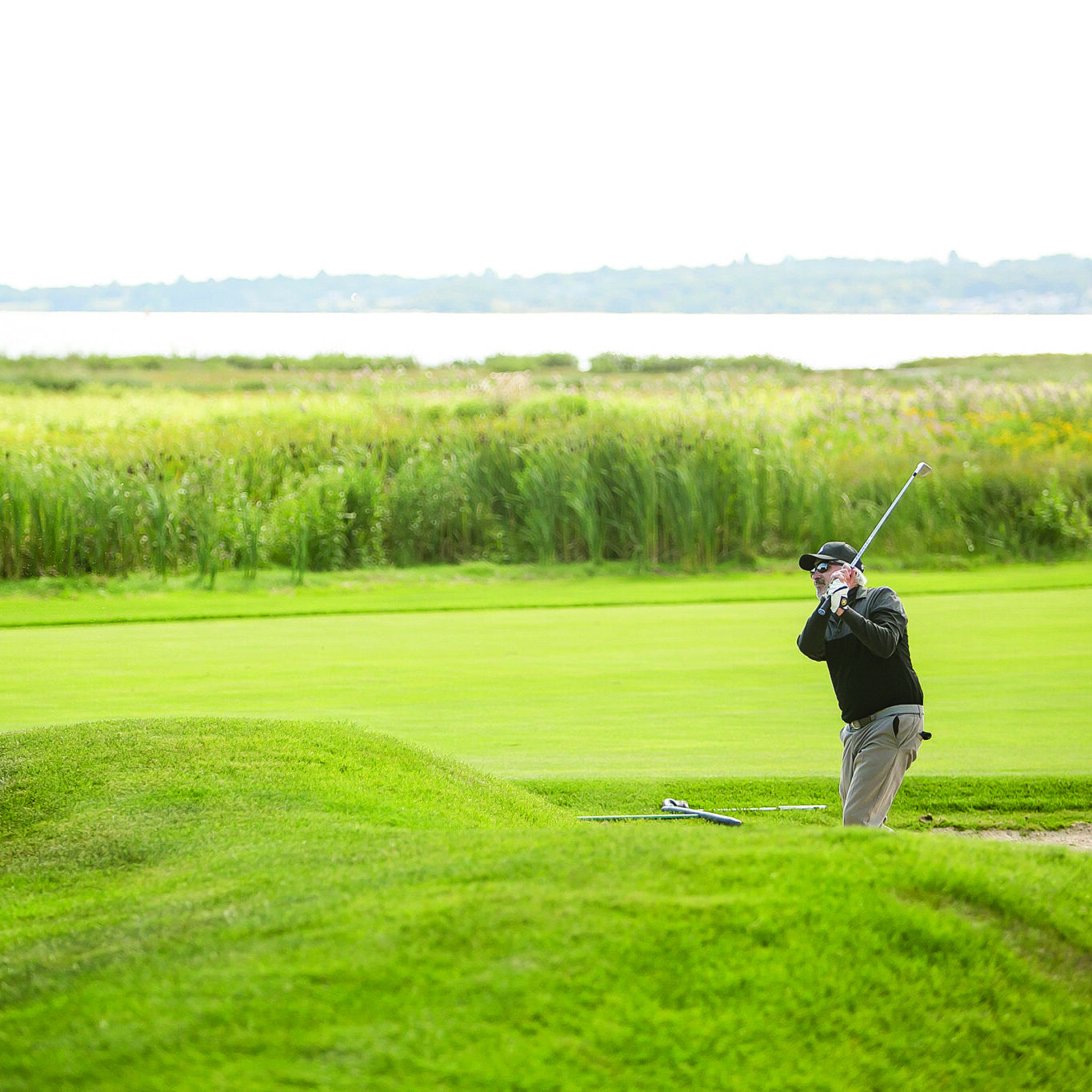 Male golfer hitting his ball up a green hill at a fundraising golf event in support of hospice