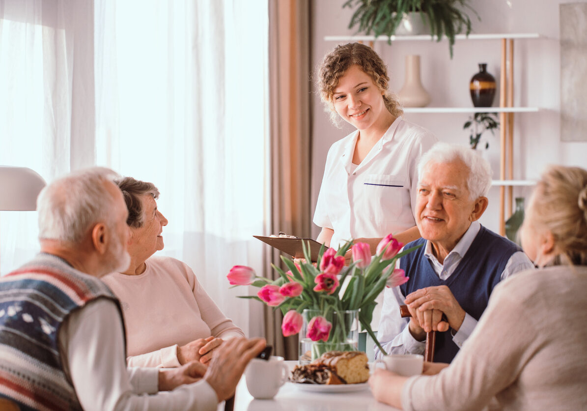 Elderly pensioners at retirement home talking during an afternoon snack