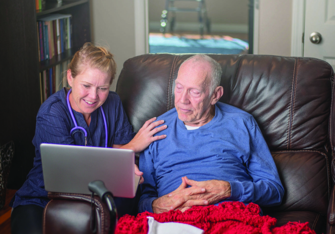 At home care giver sits with man on couch