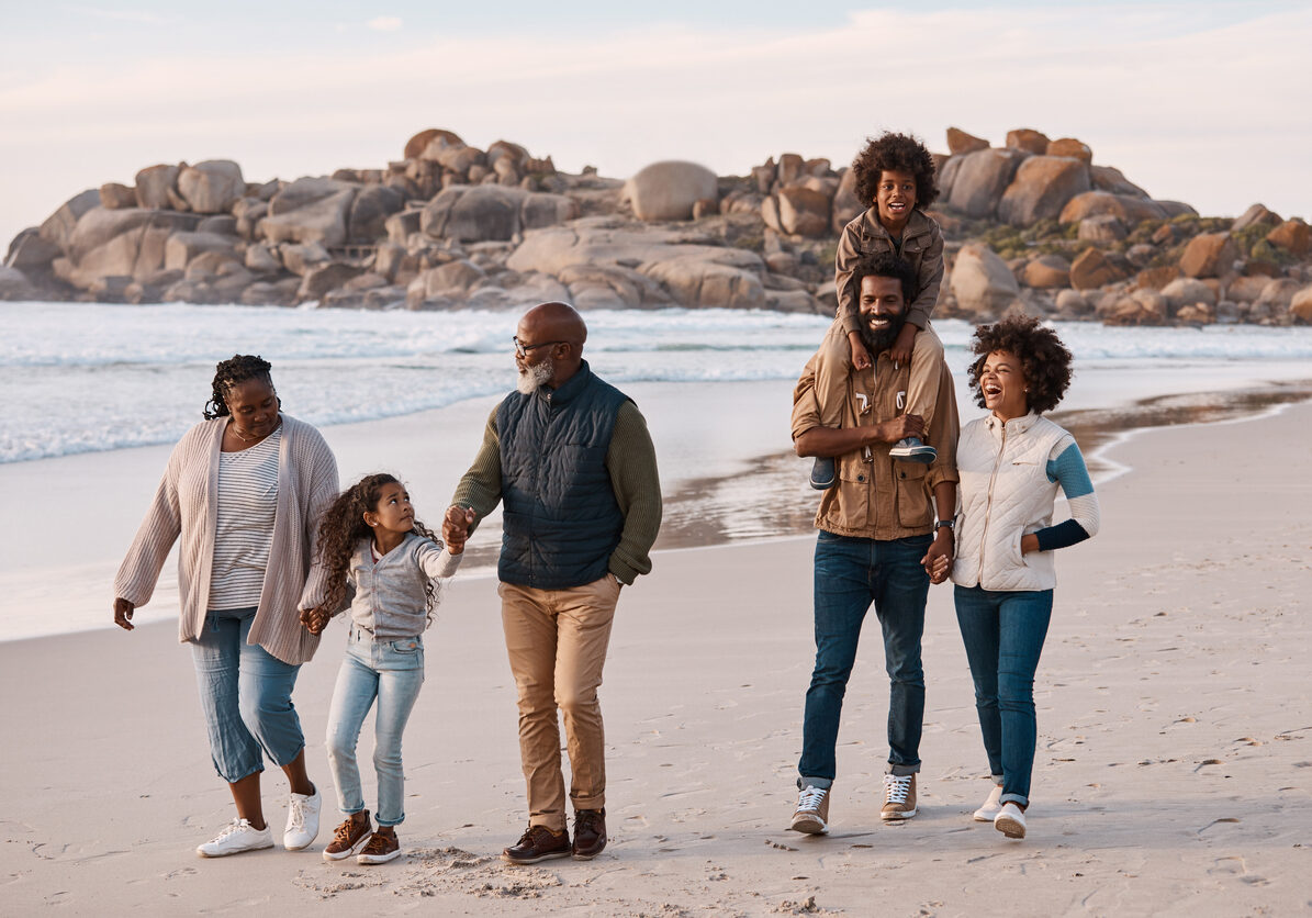 Multigenerational family on the beach. The grandfather is able to enjoy time with family because his symptoms are managed by palliative care.
