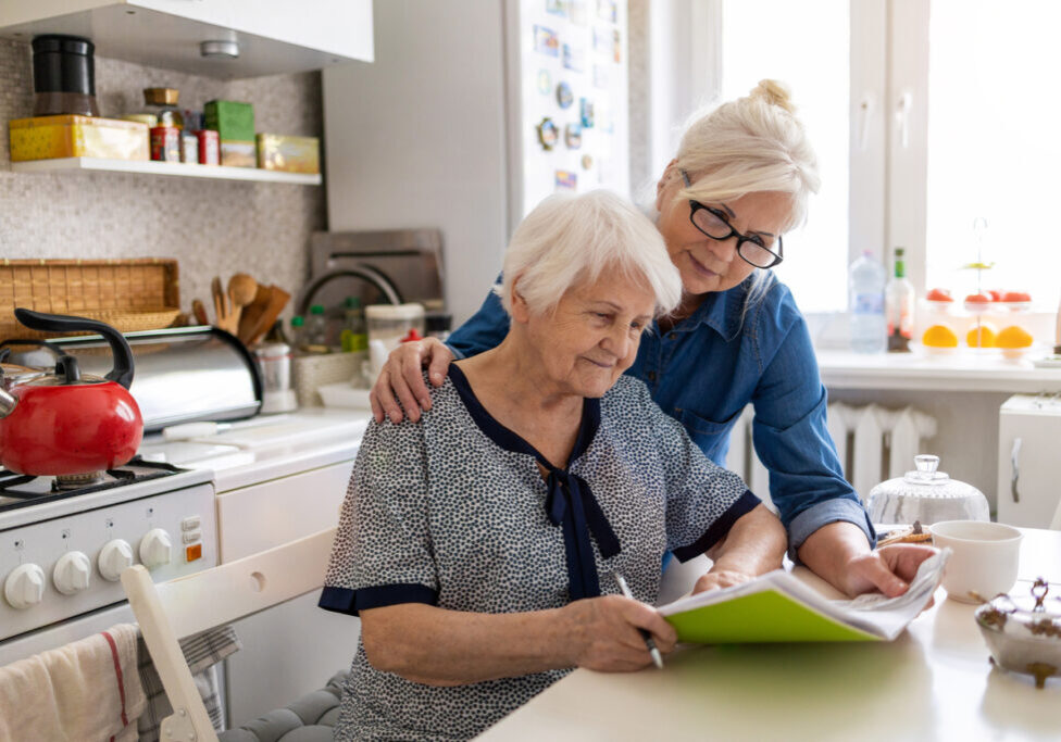 Mature woman helping elderly mother with paperwork