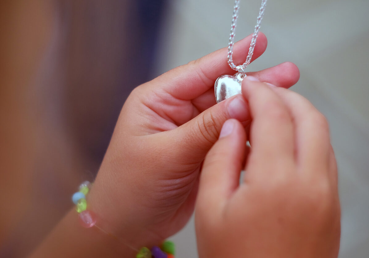 the pendant in the hands of children. Children's hands holding a beautiful chain with a pendant so close