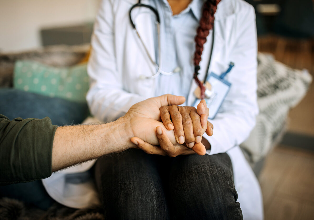 A female doctor consoles a senior patient at home