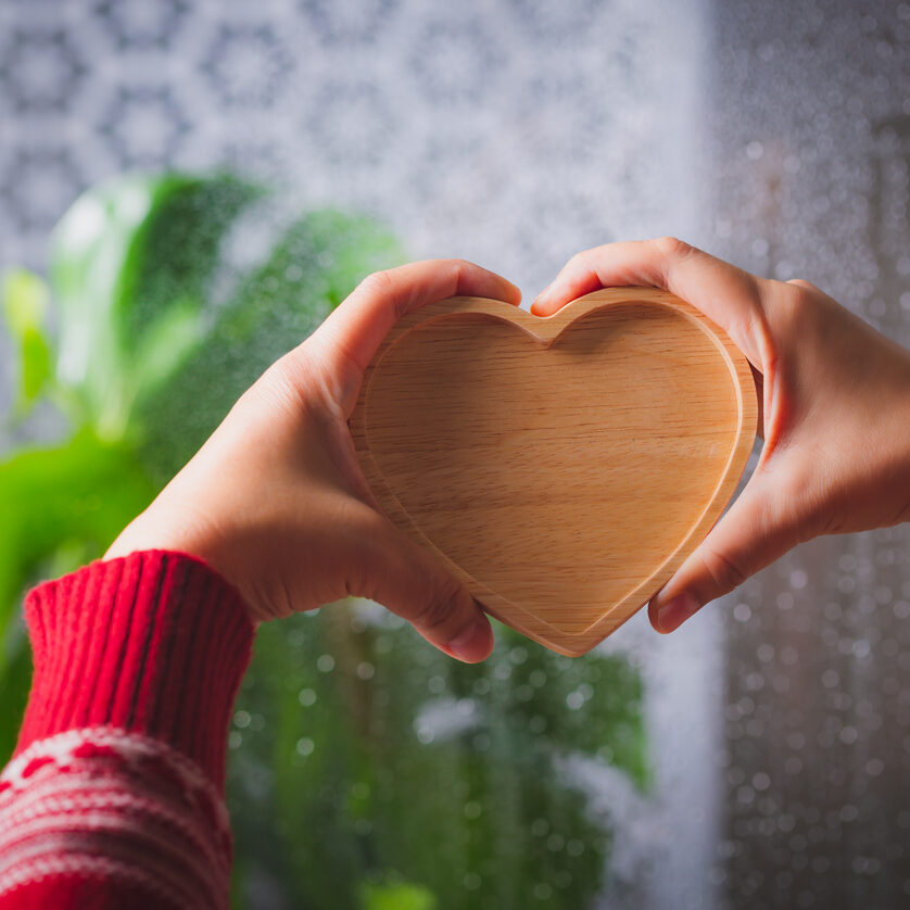 Woman hand holding wooden heart on rainy background, Valentine day concept