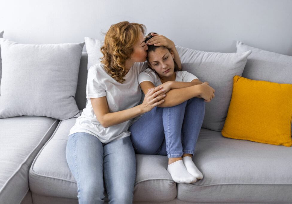 Mother Talking With Unhappy Teenage Daughter On Sofa