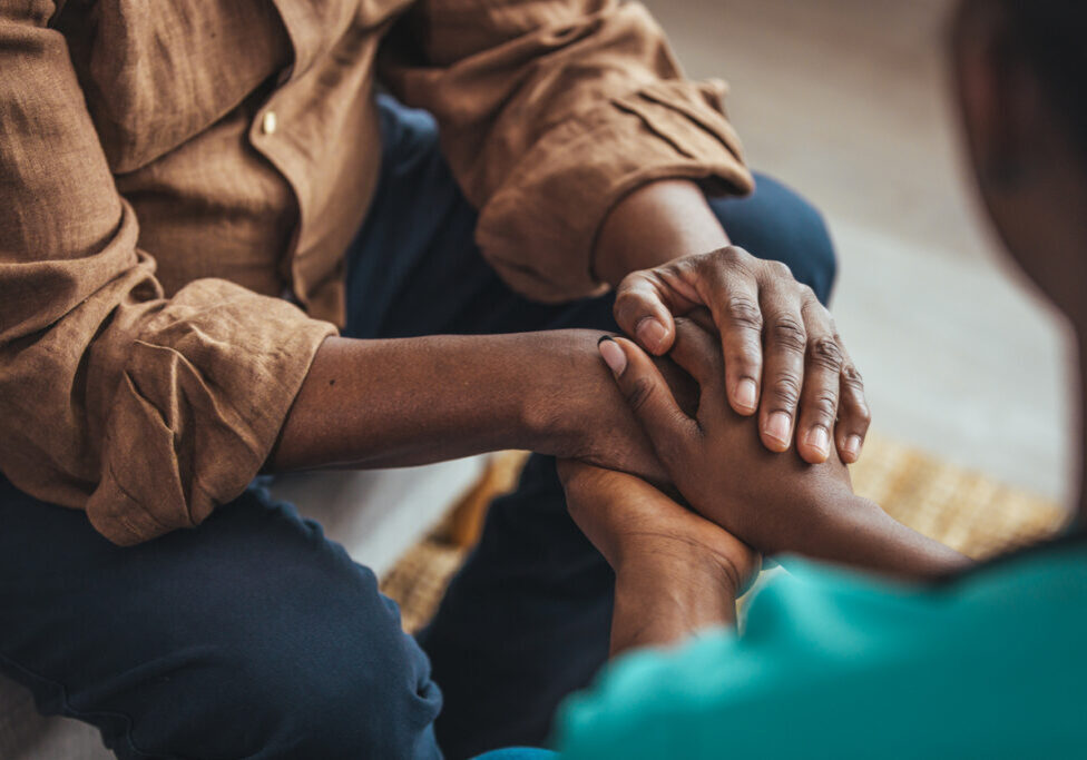 Closeup of a support hands from a social worker. Closeup shot of a young woman holding a senior man's hands in comfort. Female carer holding hands of senior man