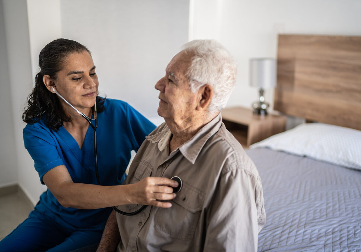 Nurse listening senior heartbeat at home