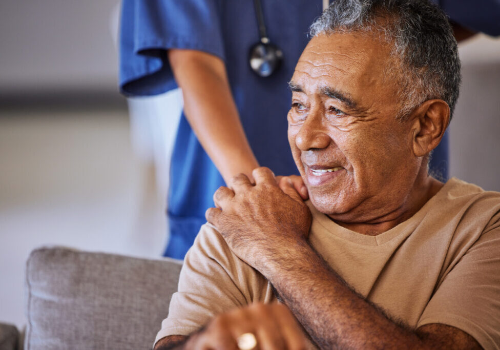 Nurse or doctor offer their man support during recovery or loss. Caregiver holding hand of her sad senior patient and showing kindness while doing a checkup at a retirement, old age home or hospital