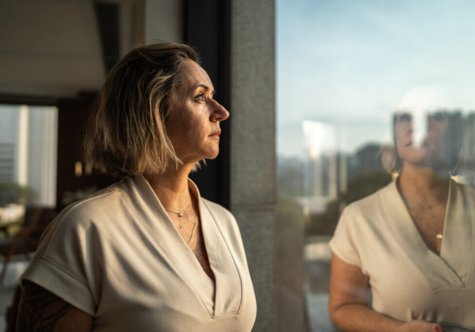 Contemplative mature woman looking through the window Contemplative mature woman looking through the window