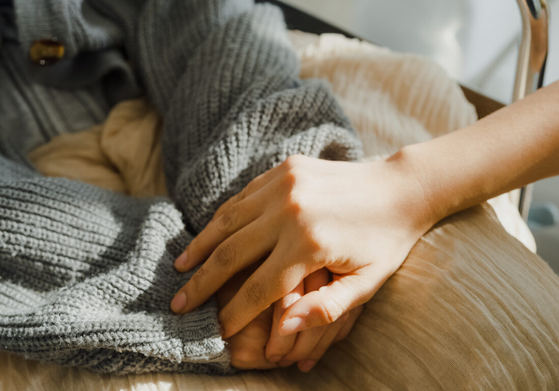 Closeup of young Asian people holding hands trust comfort help cancer patients talk crying stress relief in living room at home. Healthcare concept.