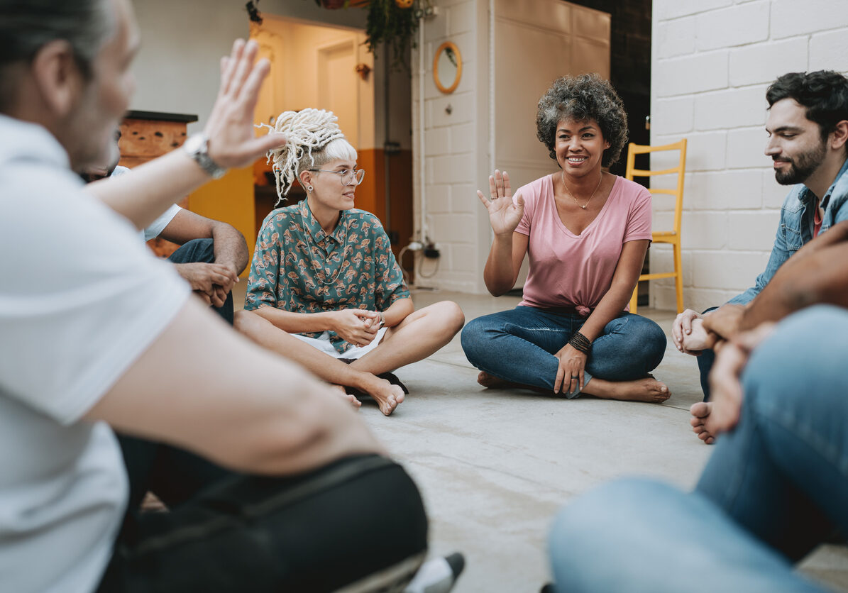 Group of people sitting cross legged in a circle for a LGBTQ+ caregiver support group