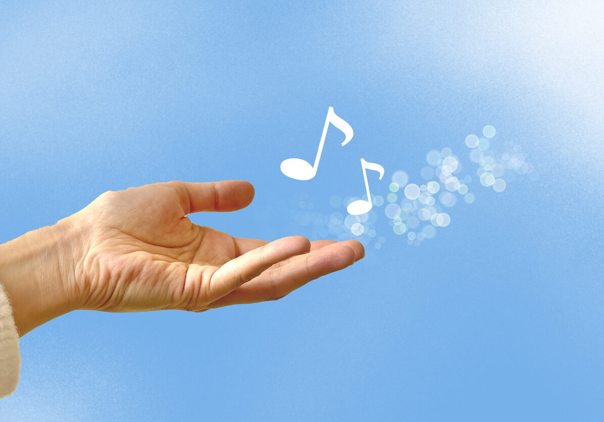 A hand outstretched over blue sky, with white music notes floating from the hand. Represents the gift of music for grief support