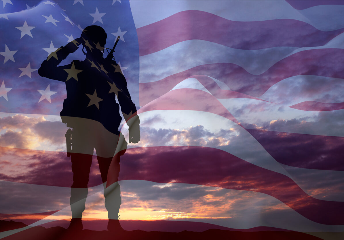 Silhouette of a soldier with USA flag against the sunset