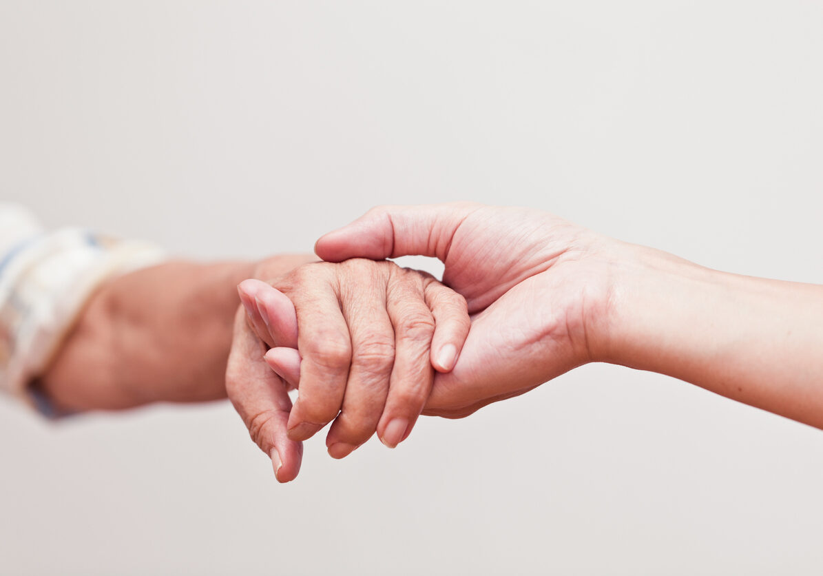 Two hands reaching out to touch in compassion, giving support for dementia patients and their caregivers