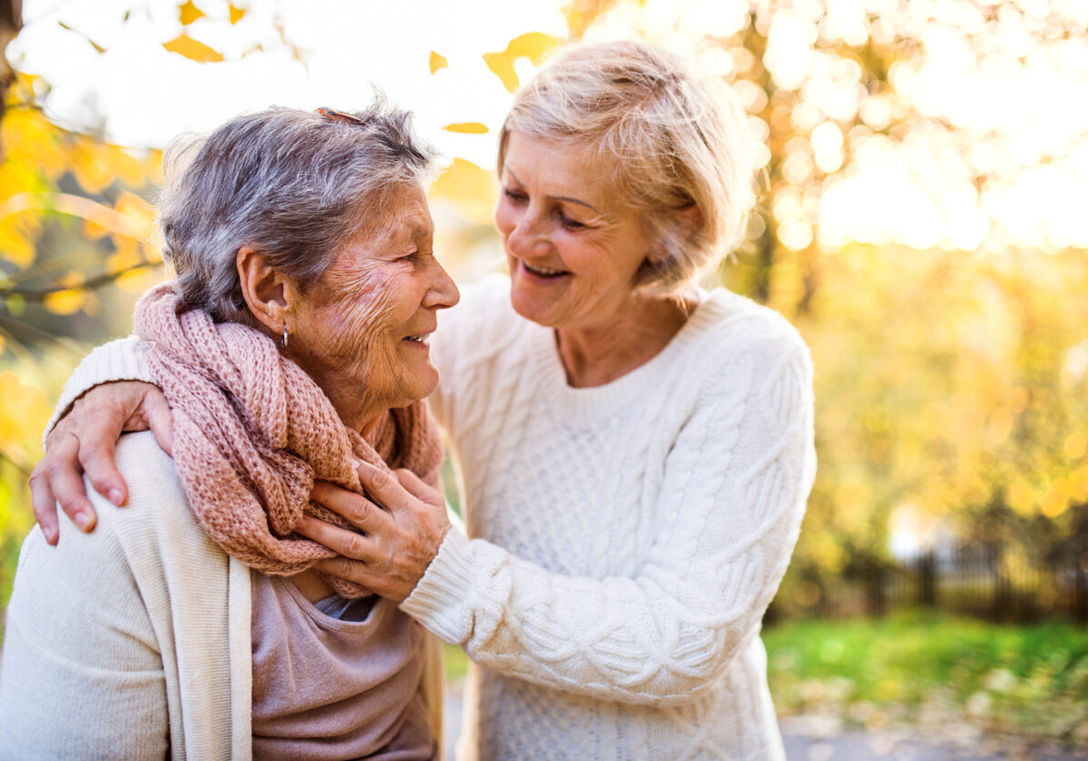 Senior women on a walk in autumn nature. An elderly woman with her senior daughter walking outside.