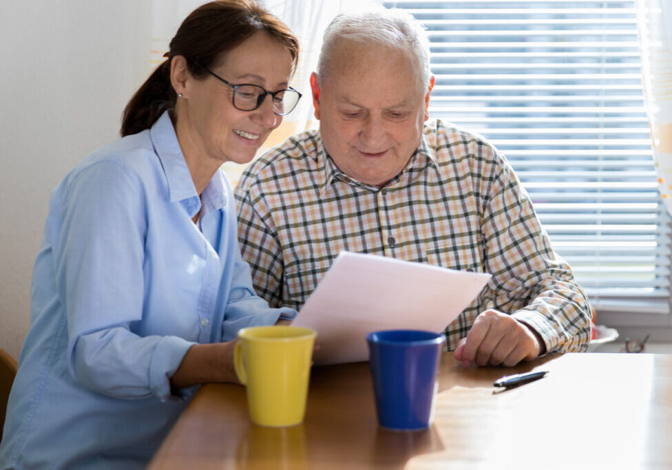 Caregiver and elderly man reading paperwork