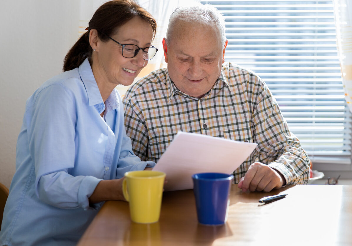 Caregiver and elderly man reading paperwork