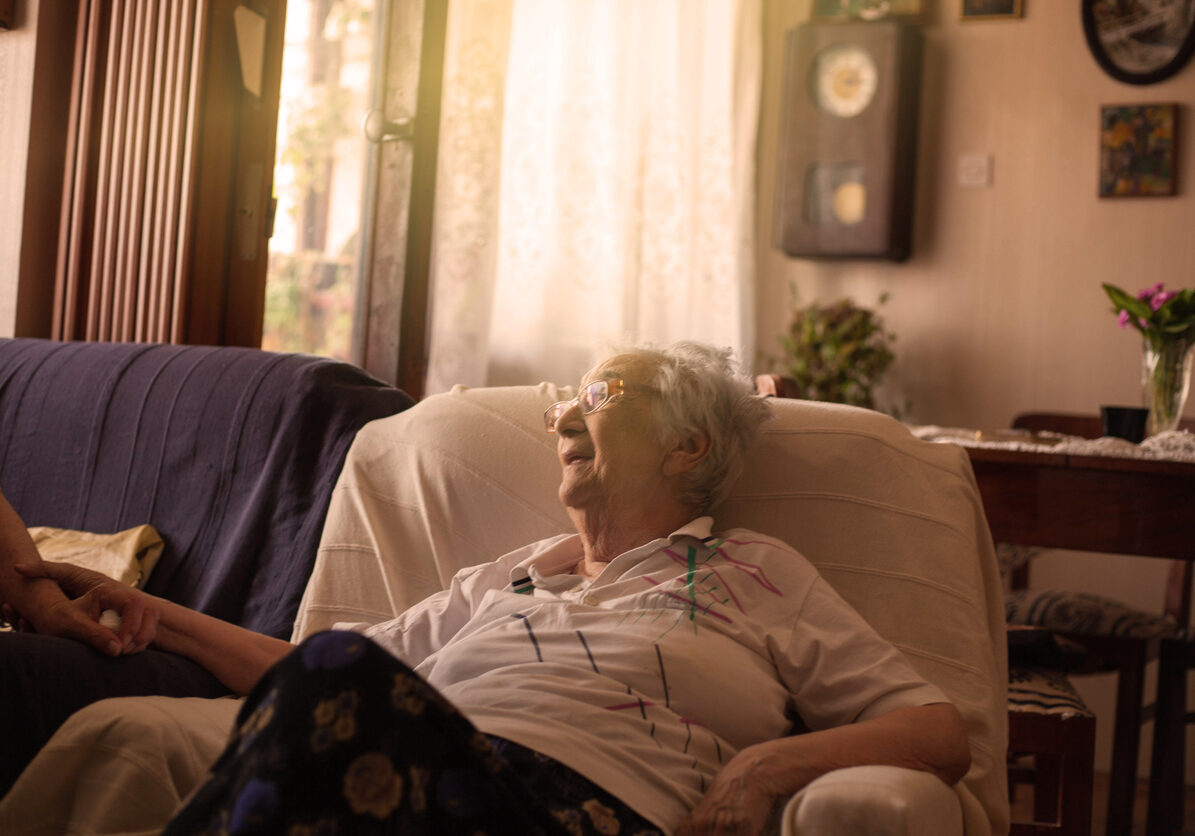 Portrait of smiling old woman sitting on sofa.